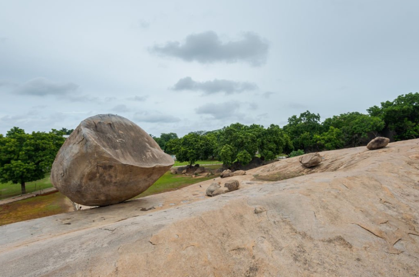 Balancing big rock boulder named _Krishna´s Butter Ball_ in Mamallapuram, Tamil Nadu, South India on cloudy day.