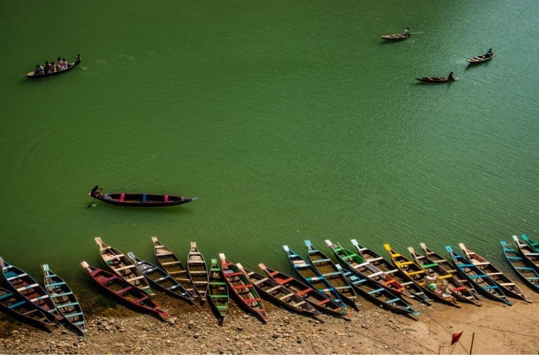 Dawki Boating Point, colorful tourist traditional wood boats isolated many at river edge image is taken at dwaki lake Meghalya, India. it is showing the pristine beauty of north east India.