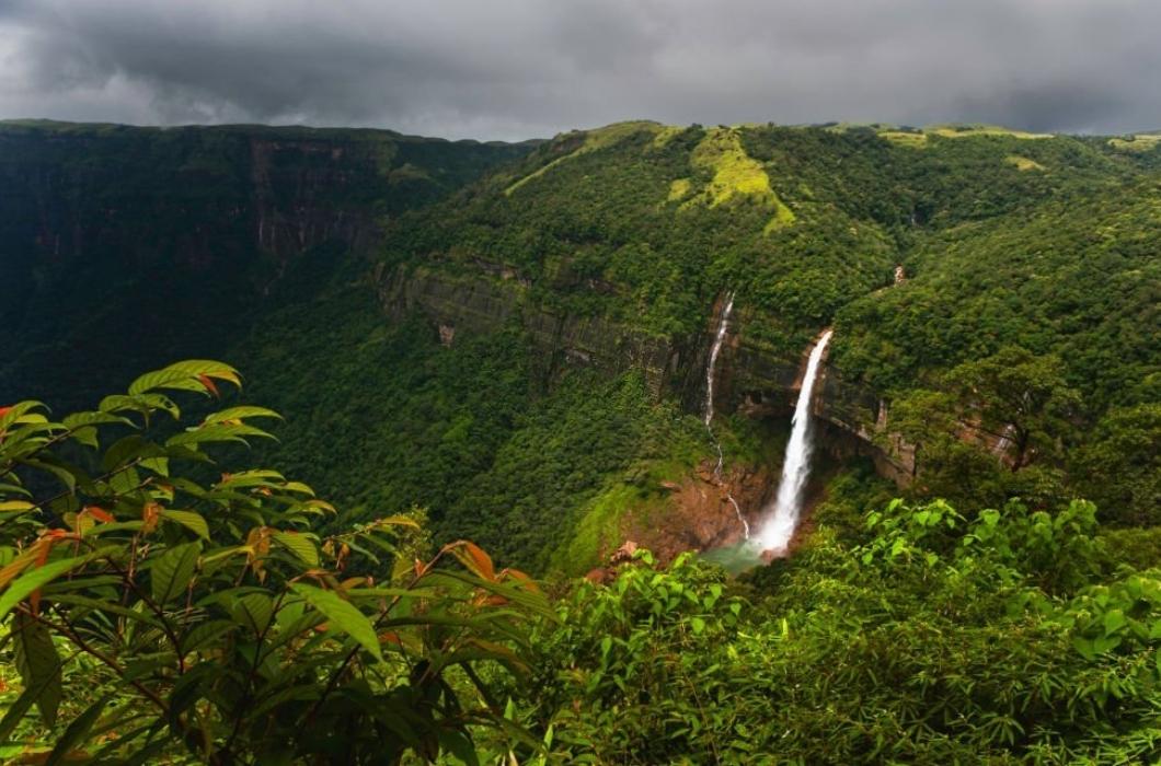 Elevated view across the Khasi hills with view of Nohkalikai waterfalls flanked by deep gorge with forested slopes under overcast sky near Shillong, Meghalaya, India.