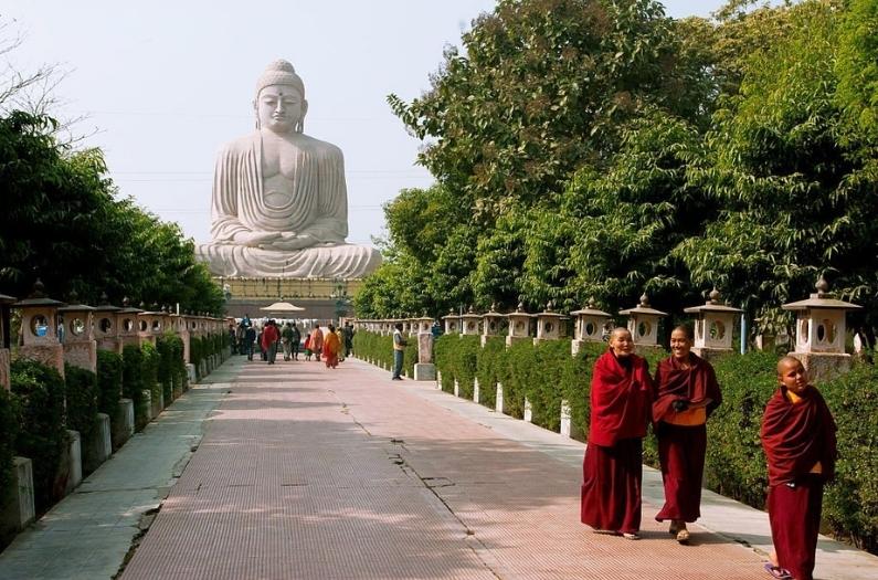 Group of Buddhist monks walking on the alley from the huge statue of Buddha.