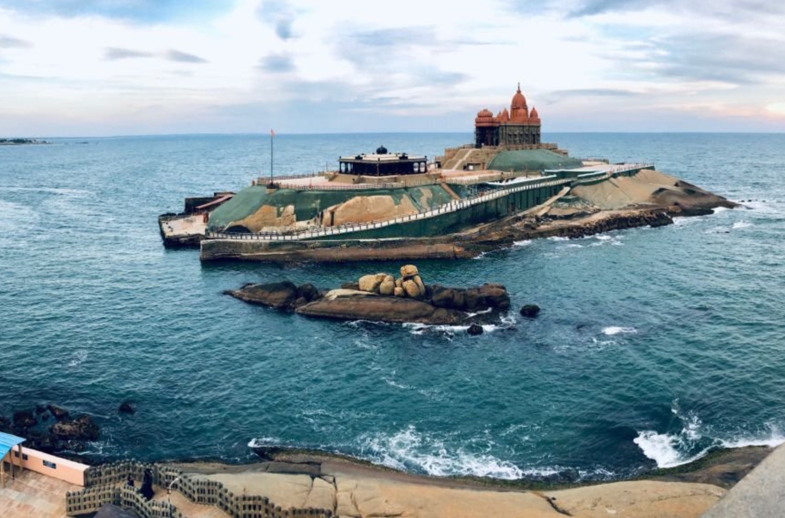 Our Lady of Ransom Shrine Church behind colorful houses on a sand beach occupied by fishing boats in Kanyakumari Beach.