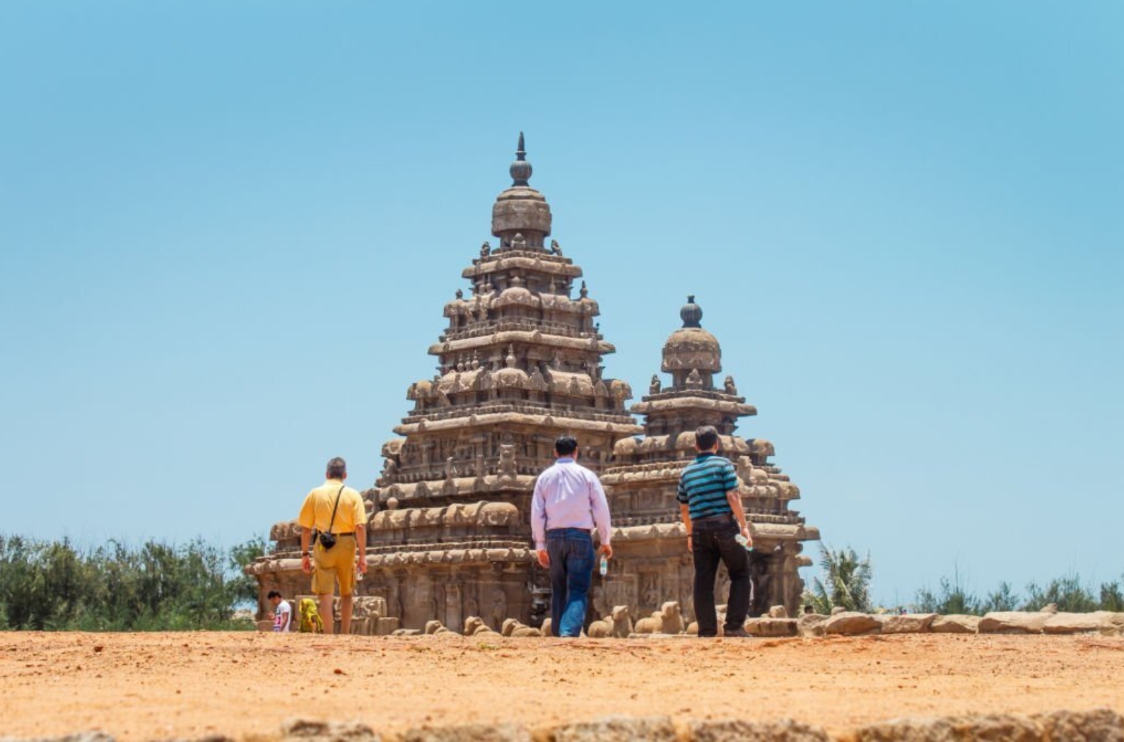 Three tourists walking to the Shore temple in Mahabalipuram, India.