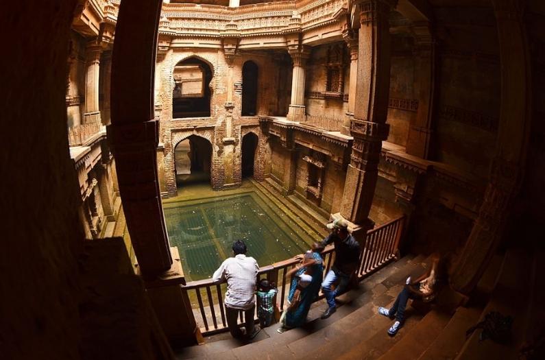 Visitors admire the beauty of architecture and carved walls of Adalaj Ki Vav - famous traditional stepwell.