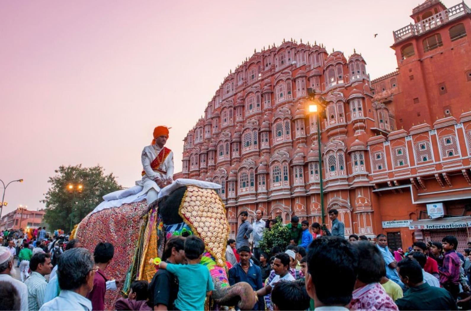 A fully dressed elephant in a parade which is part of a local Muslim festival. The background is the landmark of Jaipur, Hawa Mahal.