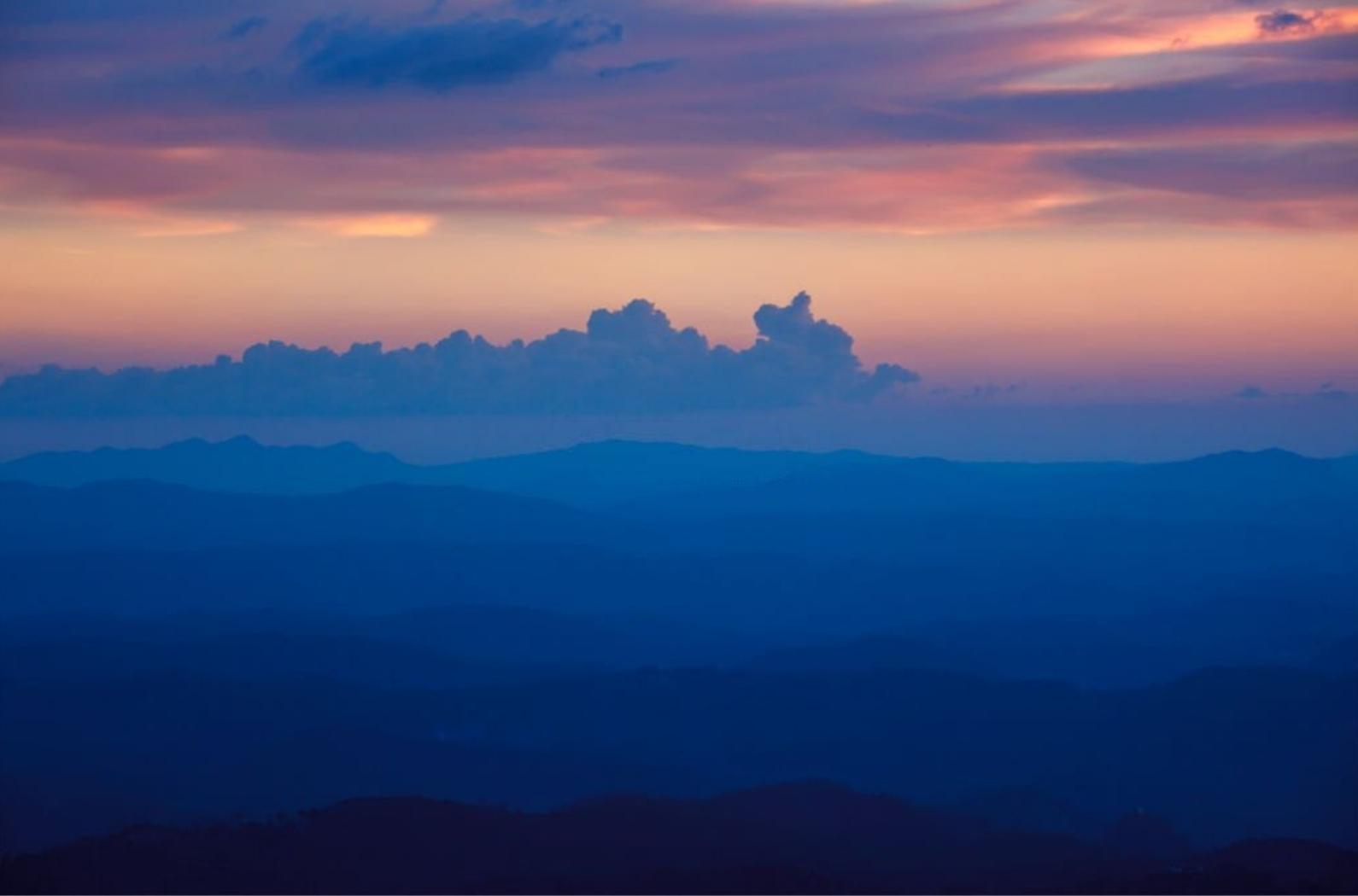 Silhouettes of hills in valley on sunset. Pothamedu viewpoint, Munnar.