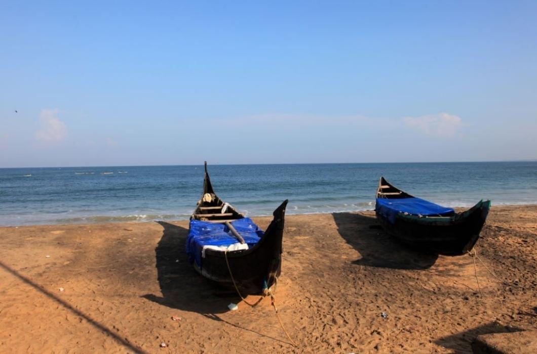Traditional wooden fishing boats docked in a beach in Kovalam Beach.