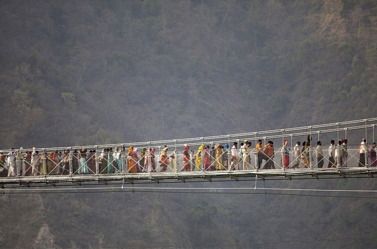 Crowd of hindu pilgrims crossing the Laksman Jhula Bridge to celebrate Kumbh Mela in Haridwar, Rishikesh India.