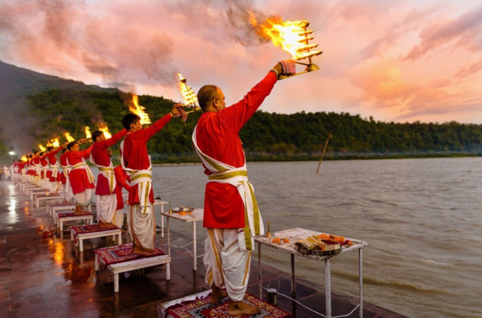 Priests in red robe in the holy city of Rishikesh in Uttarakhand, India during the evening light ceremony called Ganga arthi to worship river Ganga _ Ganges.