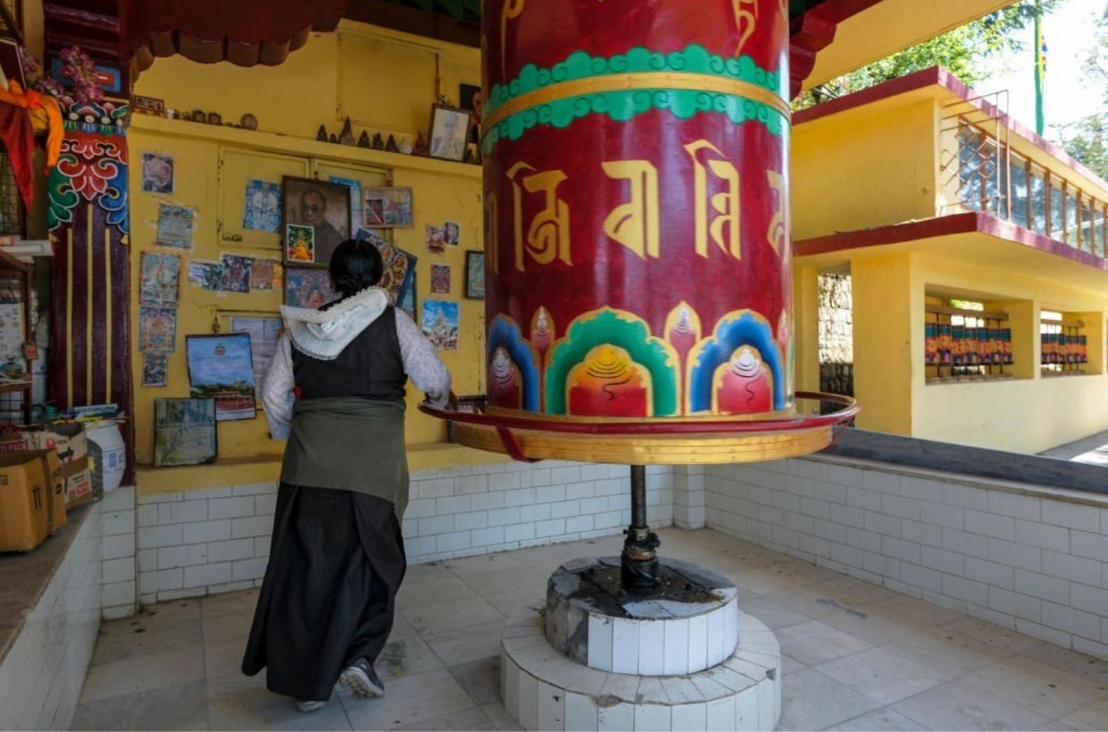 Tibetan woman spinning a prayer wheel at the Tsuglagkhang Complex.
