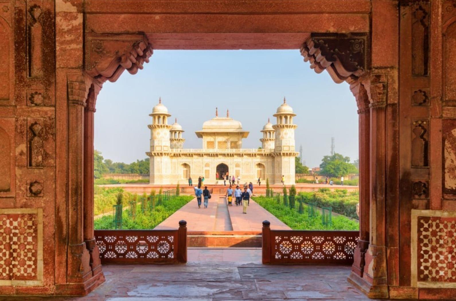 Unusual view of the Tomb of Itimad-ud-Daulah (Baby Taj) through red sandstone gate. The white marble mausoleum is a popular tourist attraction of South Asia.