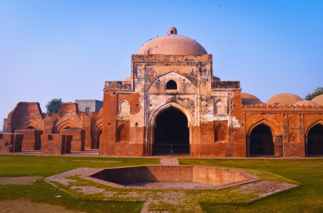 Landscape photos of Kabuli bagh masjid front side with one side damaged Tomb and wall blue sky and green grass, Panipat, India.