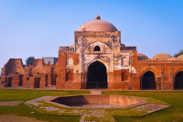 Landscape photos of Kabuli bagh masjid front side with one side damaged Tomb and wall blue sky and green grass, Panipat, India.