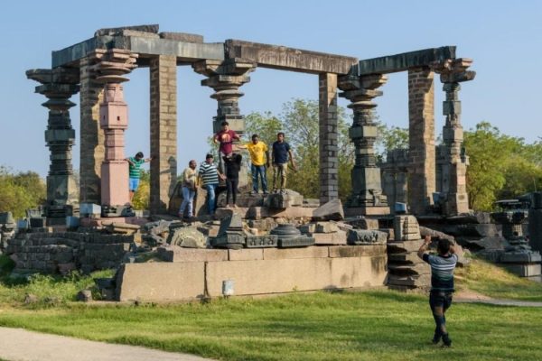 Tourists around the old, ruined remnants of an ancient temple inside the Warangal Fort.